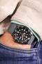 Pocket shot of a Seiko 5 Sports in jeans pocket with turquoise hoodie and cream cord shirt, the watch is fitted to a grey rubber strap