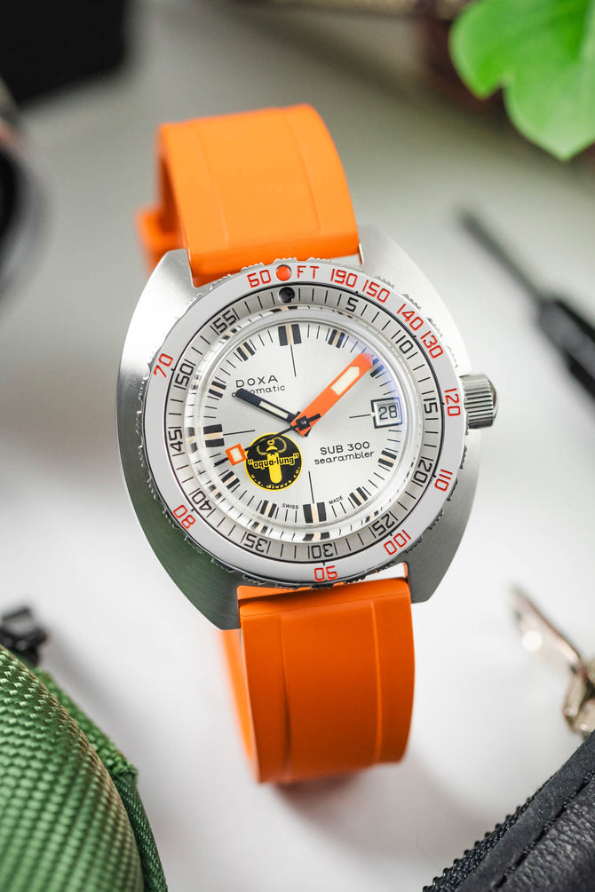 An orange universal 20mm watch strap matching the hands and bezel details of a Doxa SUB 300 Searambler watch