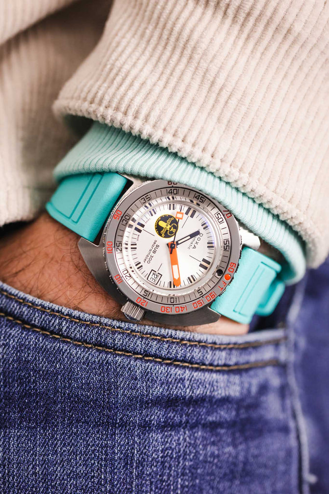 Pocket shot of a Doxa Silverlung dive watch in jeans pocket with turquoise hoodie and cream cord shirt, the watch is fitted to a Turquoise rubber strap